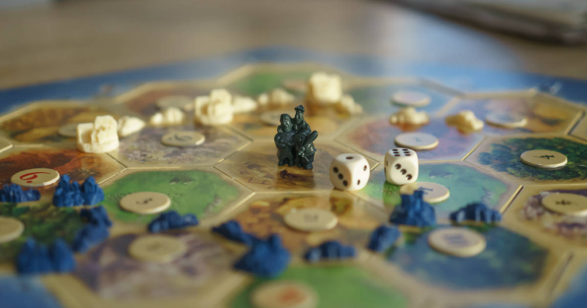 A board game in progress with a miniature, dice and hexagon playing field.